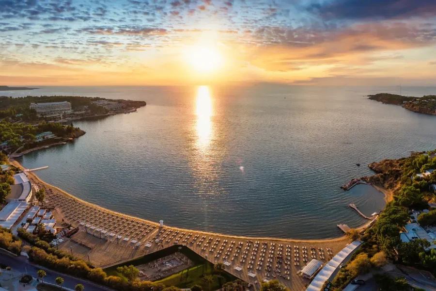 Sunset view along the Athens Riviera coastline with golden light over the sea and coastal landscape.