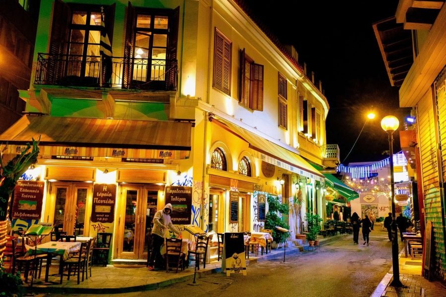 Traditional Greek taverna in Athens at night with warm lights and outdoor tables in Psiri neighborhood.