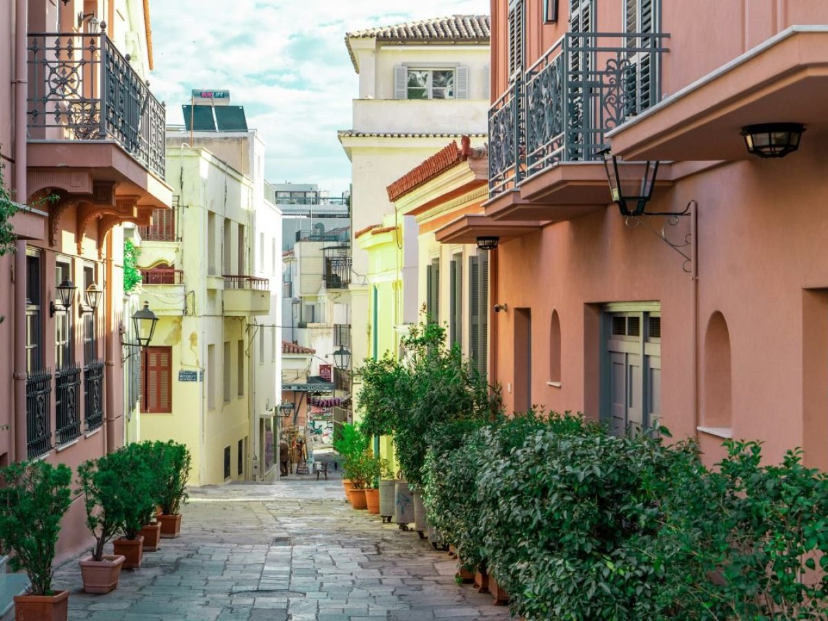 Quiet neoclassical street in Athens with pastel buildings and greenery, reflecting a calm, local walking experience